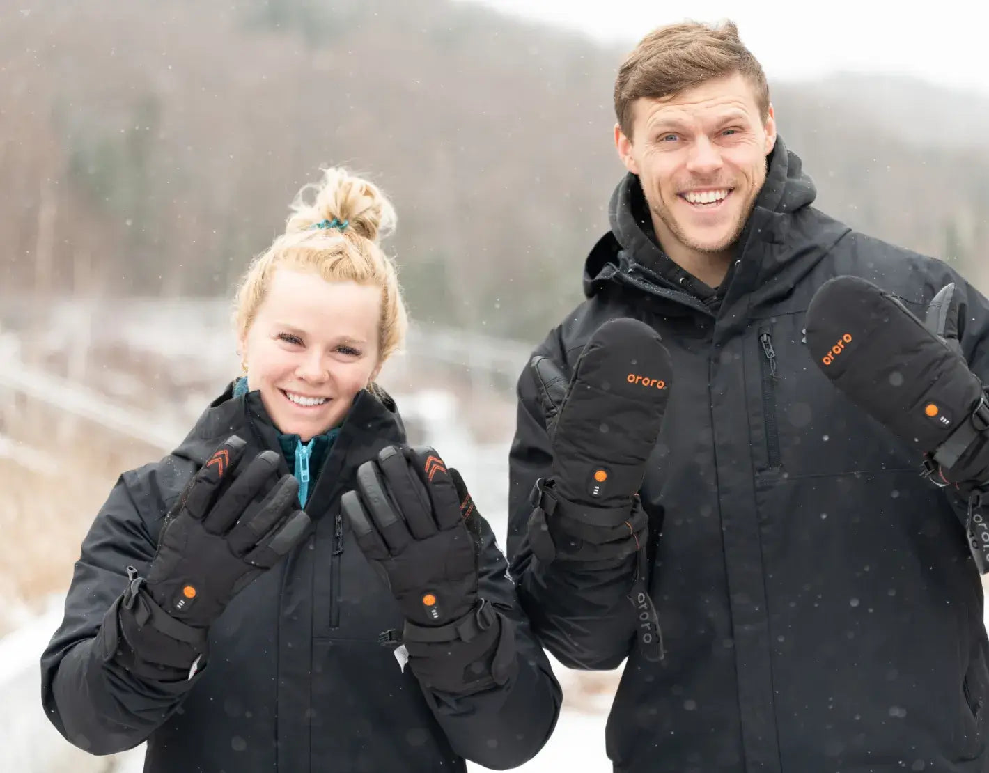 Two people wearing black gloves with orange accents in a snowy landscape