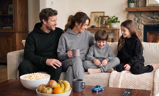 Family wearing Ororo Toasty Unisex 5-Zone Heated Pullover Hoodie and Sweatpants, relaxing together on a sofa at home with cozy indoor comfort and warmth.