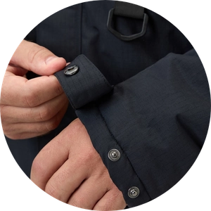 Close-up of a hand fastening the cuff of a black long-sleeve button-up shirt.