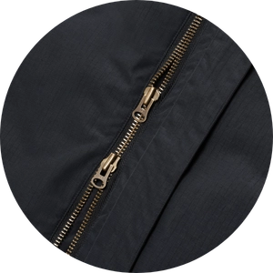 Close-up detail of a black fabric jacket with a gold-toned zipper 