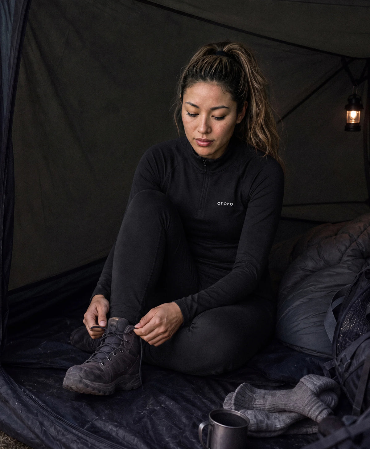 Woman wearing heated top and bottom with ororo logo inside tent