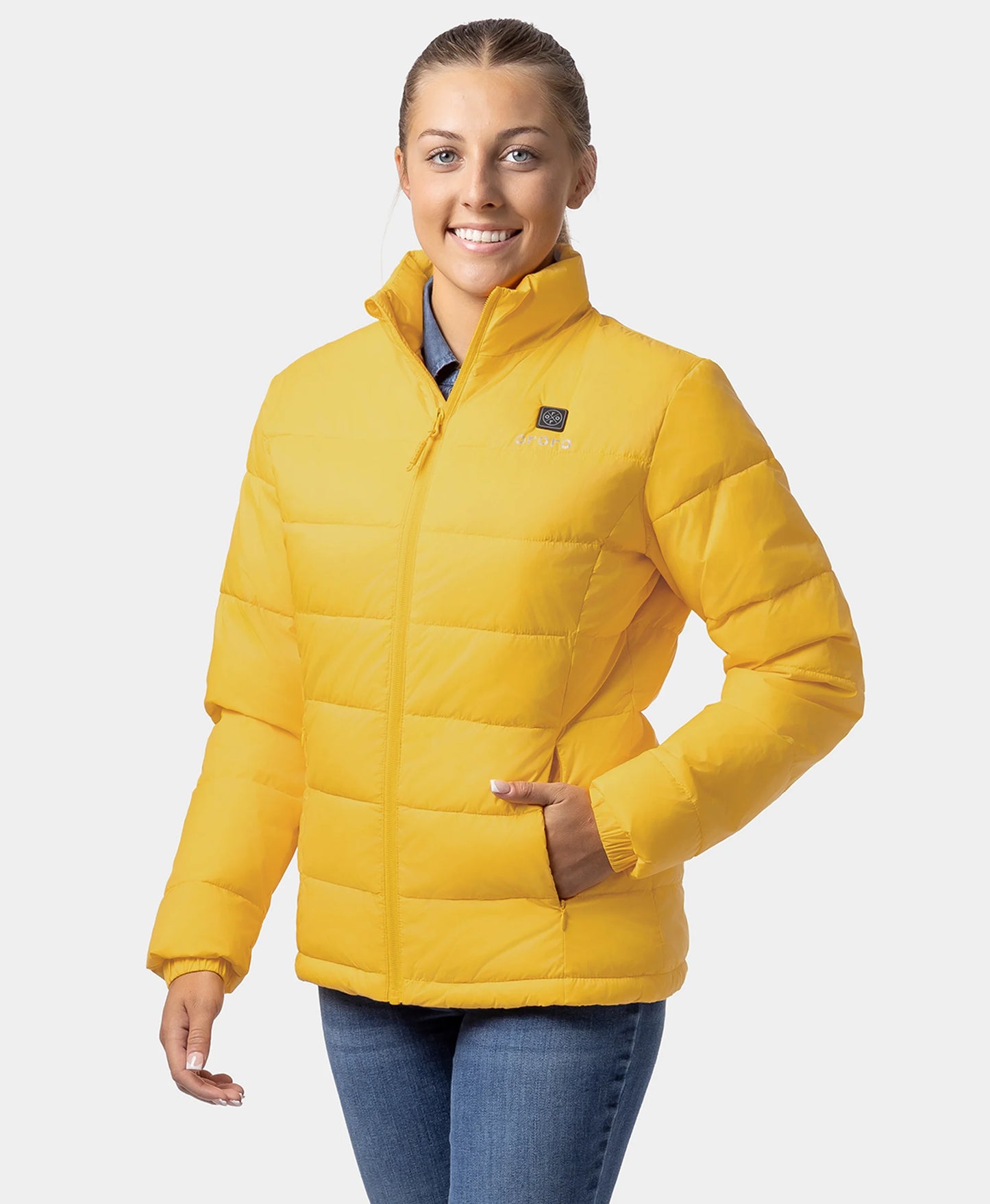 A woman wearing a bright yellow puffer ororo Heated Puffer Jacket with a stand-up collar and front zipper, paired with blue jeans, photographed against a light gray studio background.
