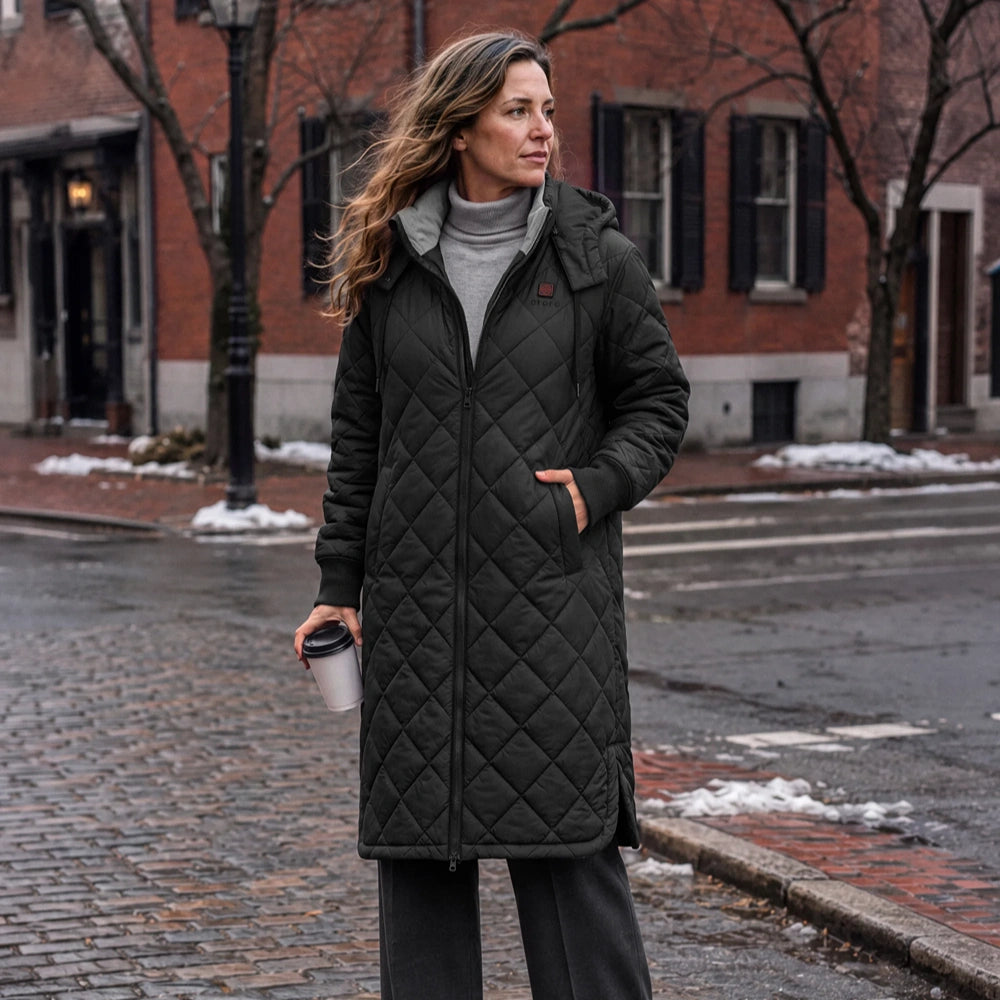 Uptown Women's 4-Zone Heated Parka in black, worn outdoors on a snowy city street