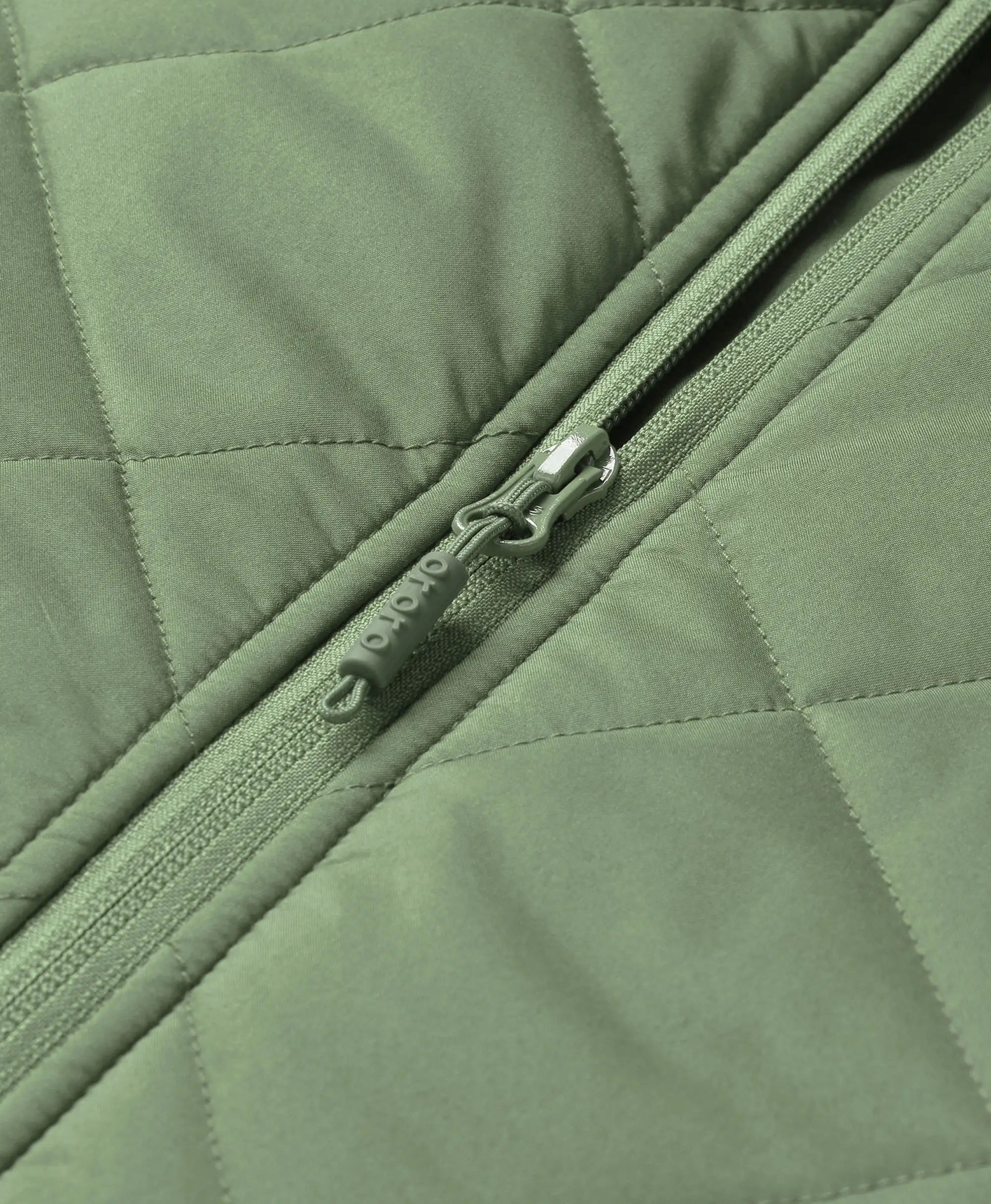 Close-up of hedge green ororo Women's Heated Quilted Vest front zipper featuring an embossed ororo logo on the zipper pull tab