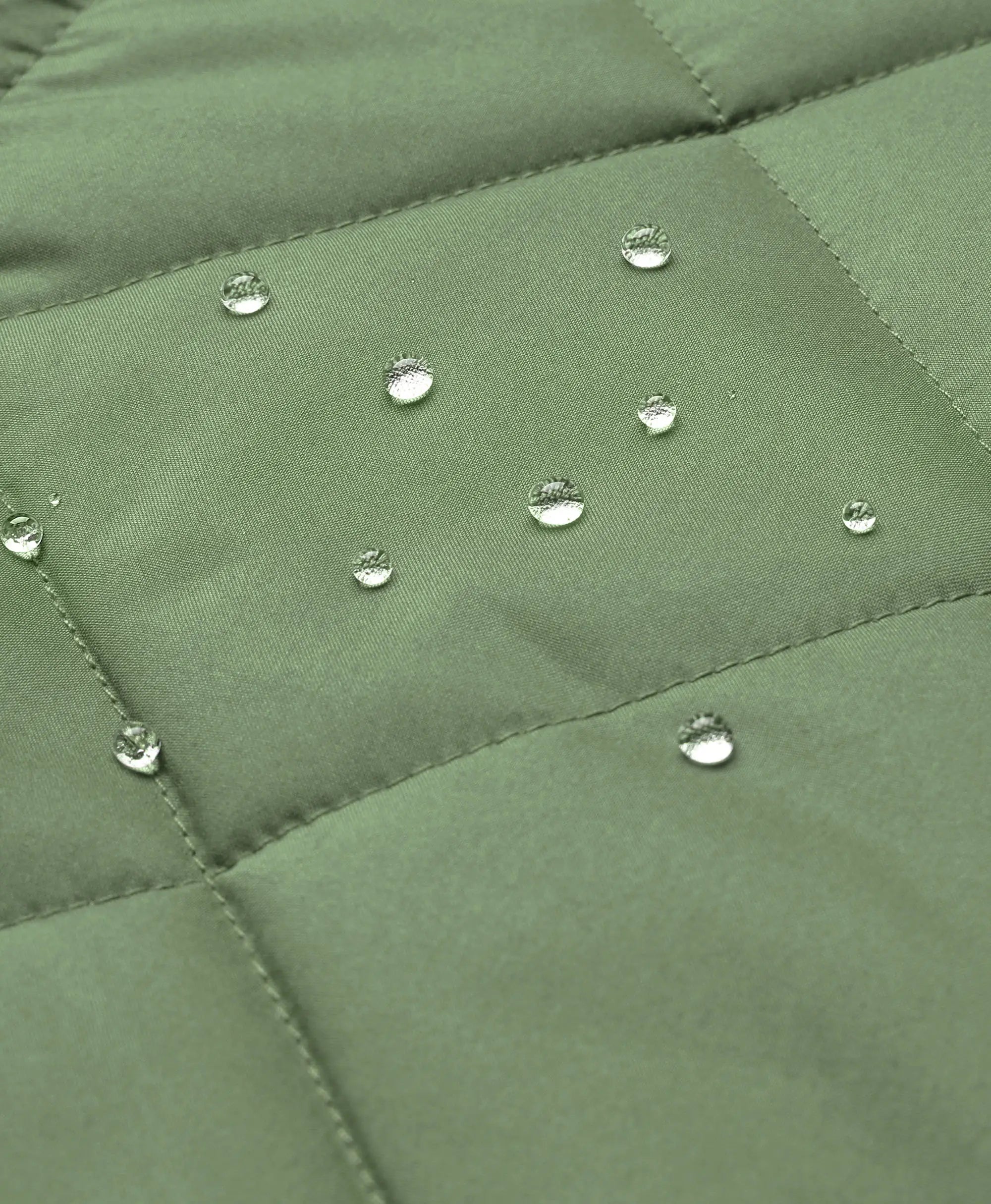 Close-up of an olive green quilted fabric surface with several clear water droplets resting on the material.