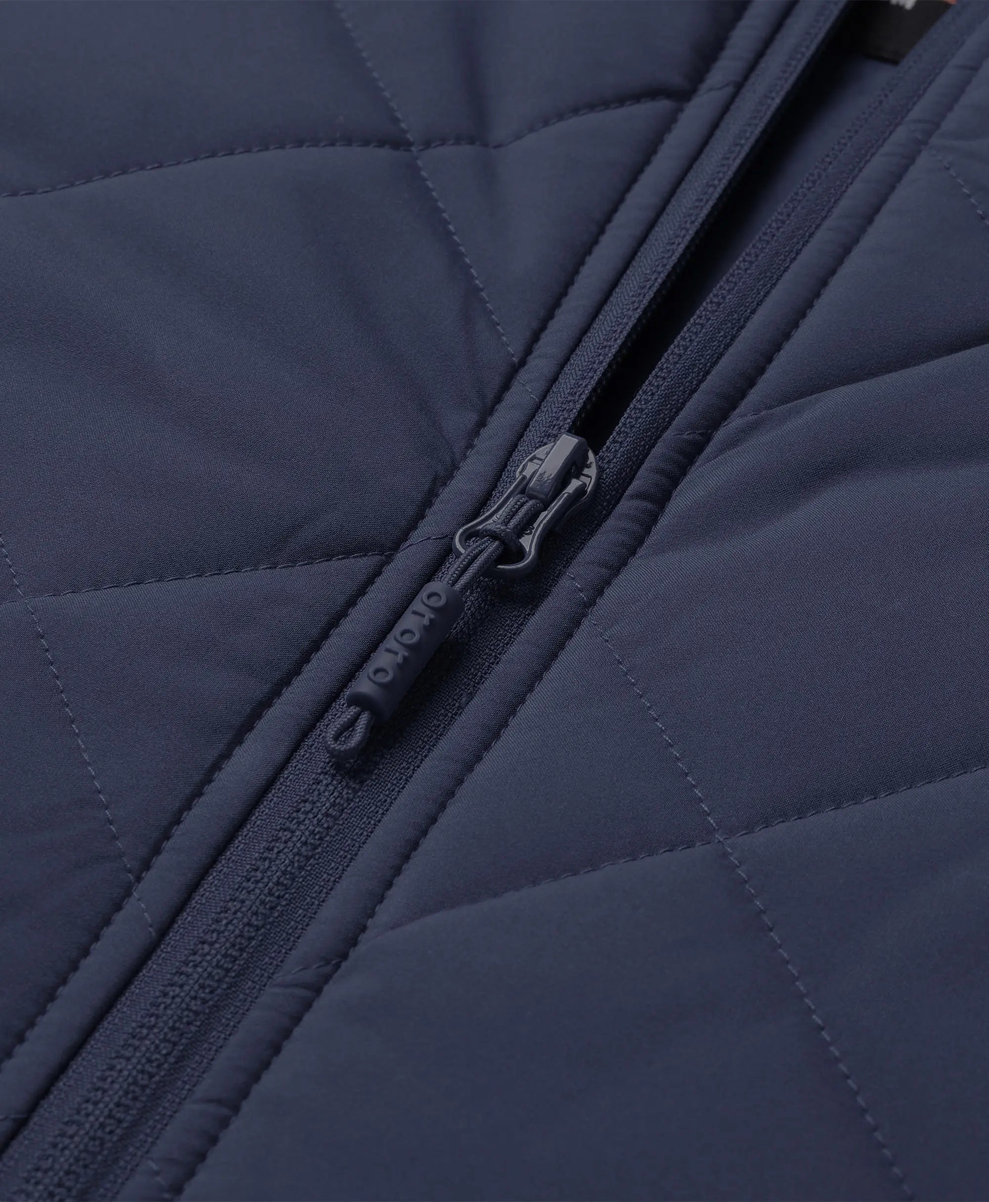 Close-up of navy blue ororo Women's Heated Quilted Vest front zipper featuring an embossed ororo logo on the zipper pull tab