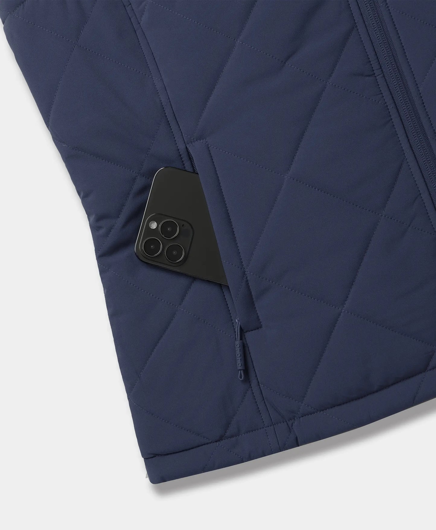 Close-up of a navy blue quilted jacket with a side pocket holding a black smartphone, showing the texture and zipper details against a light gray background.