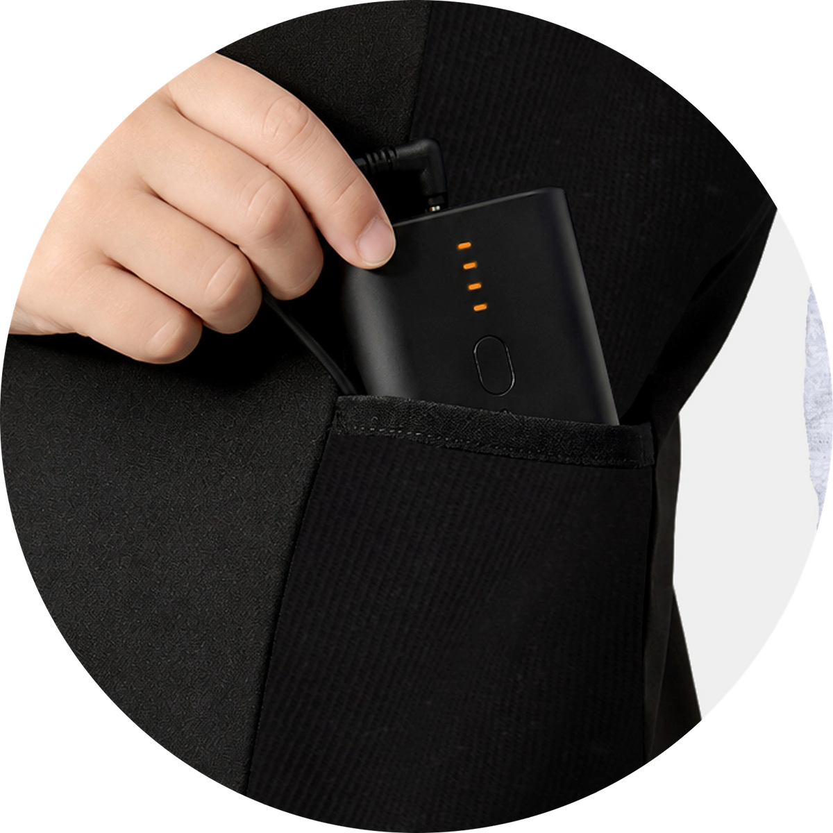 Hand placing a black power bank battery into the pocket of a vest