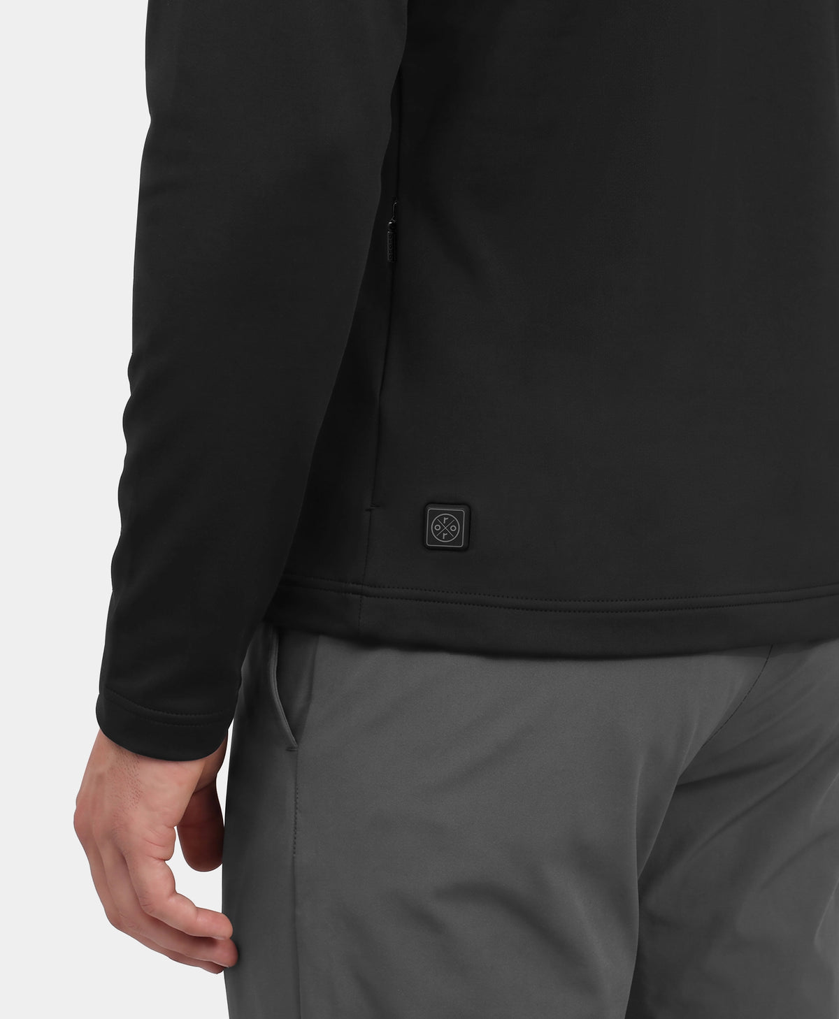 Man wearing black heated base layer top and gray pants, showing lower back heated logo detail