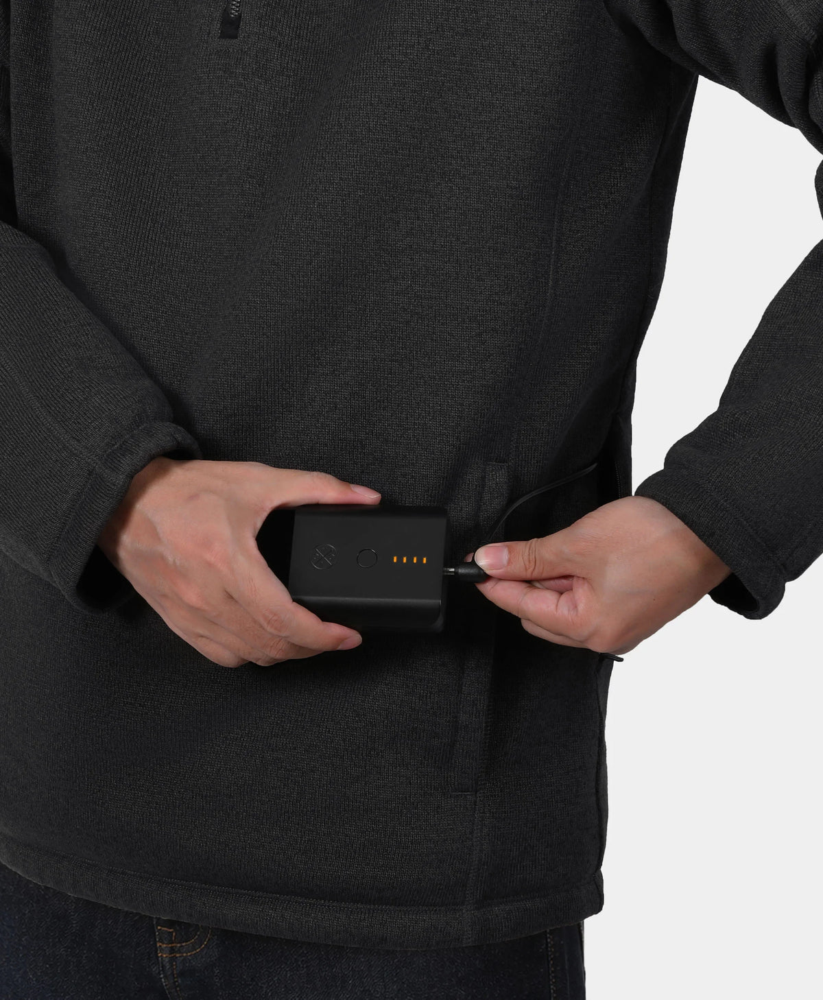 A close-up of a person wearing ororo fleece pullover jacket and plugging a small black battery