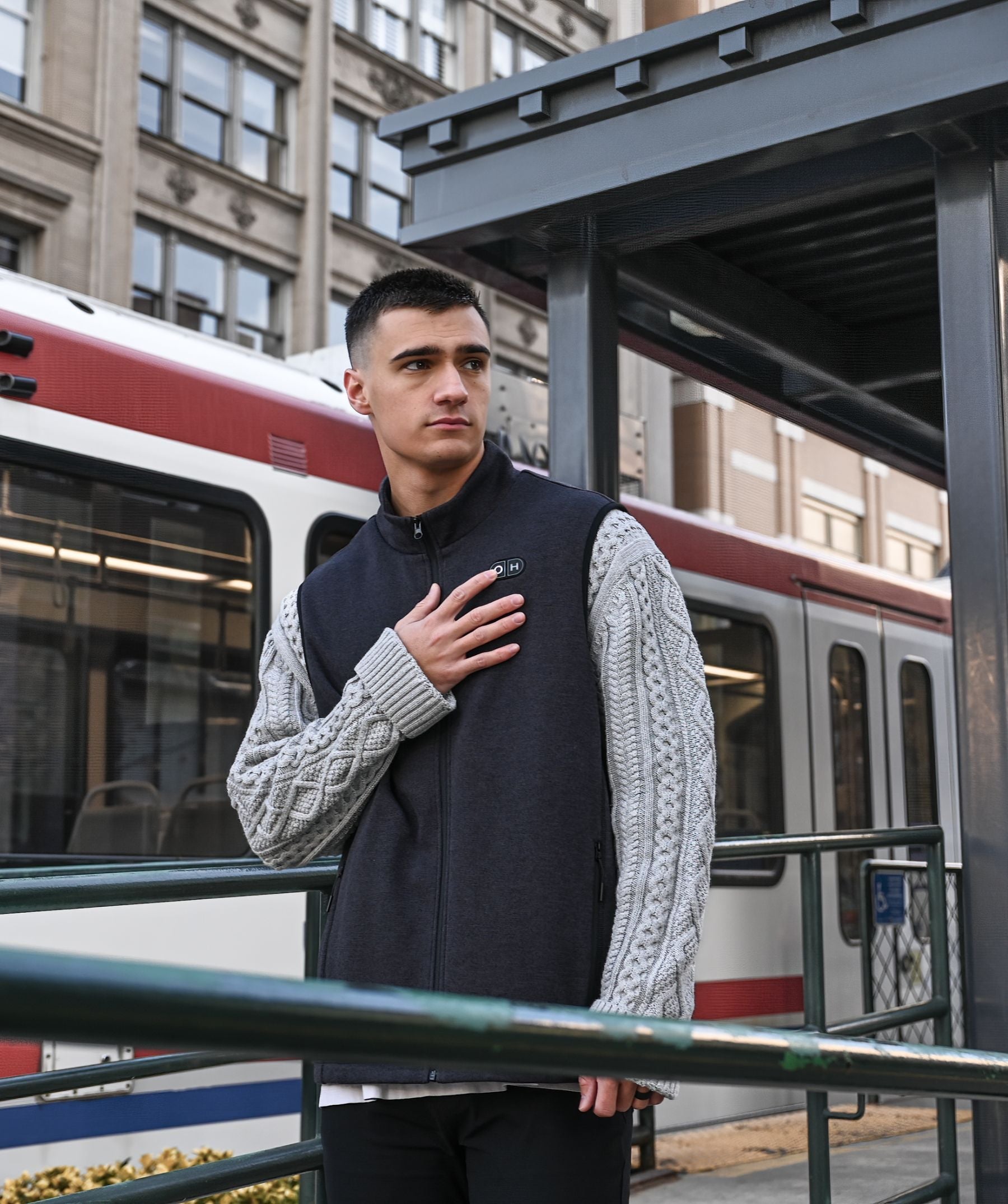 A  man with the vest staying at a tram station