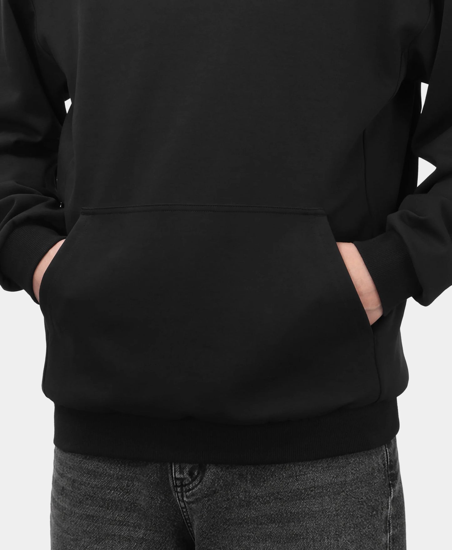 A black Toasty Unisex 5-Zone Heated Pullover Hoodie, shown in a close-up detail of the front kangaroo pocket with a model placing their hands inside.
