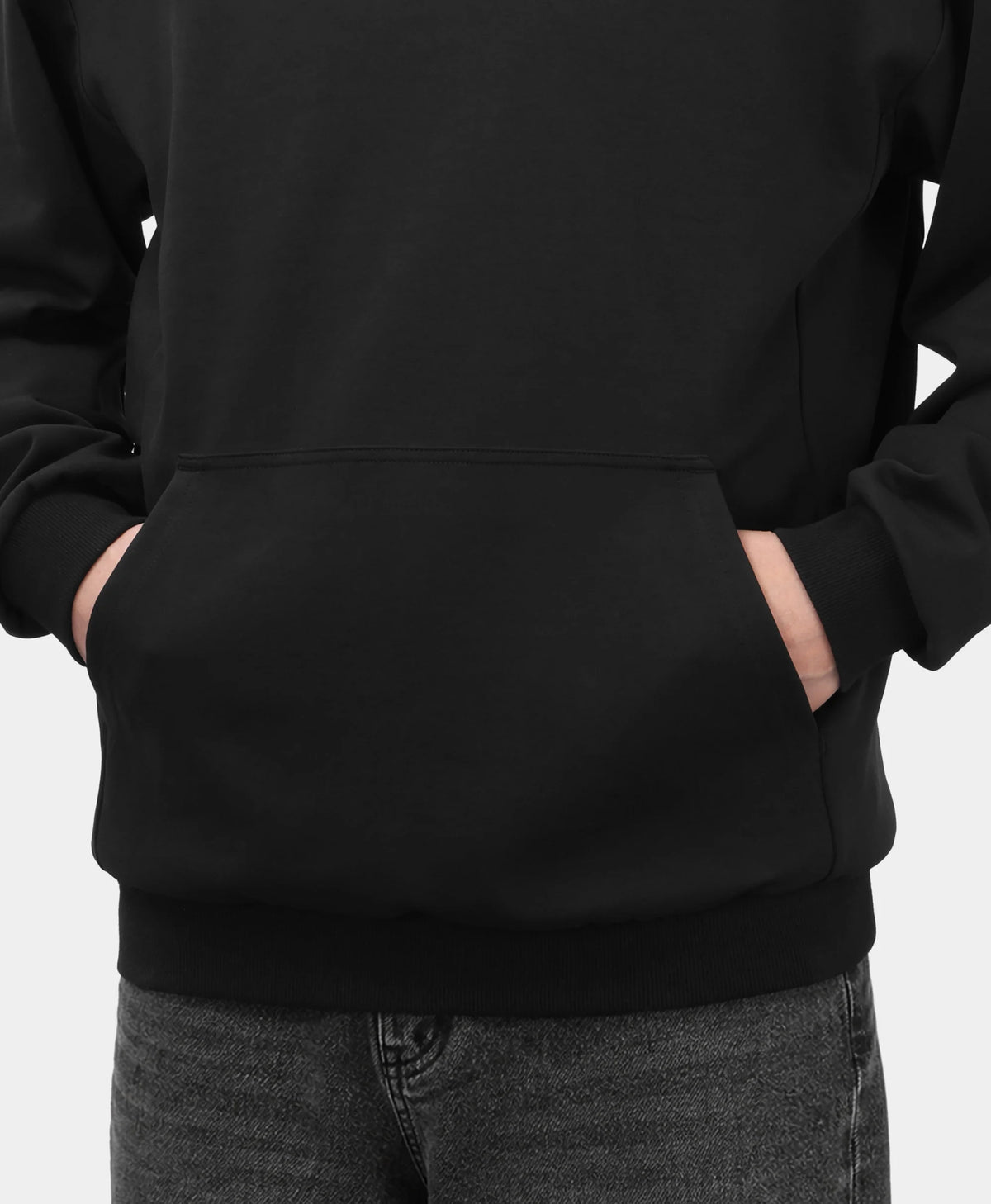A black Toasty Unisex 5-Zone Heated Pullover Hoodie, shown in a close-up detail of the front kangaroo pocket with a model placing their hands inside.
