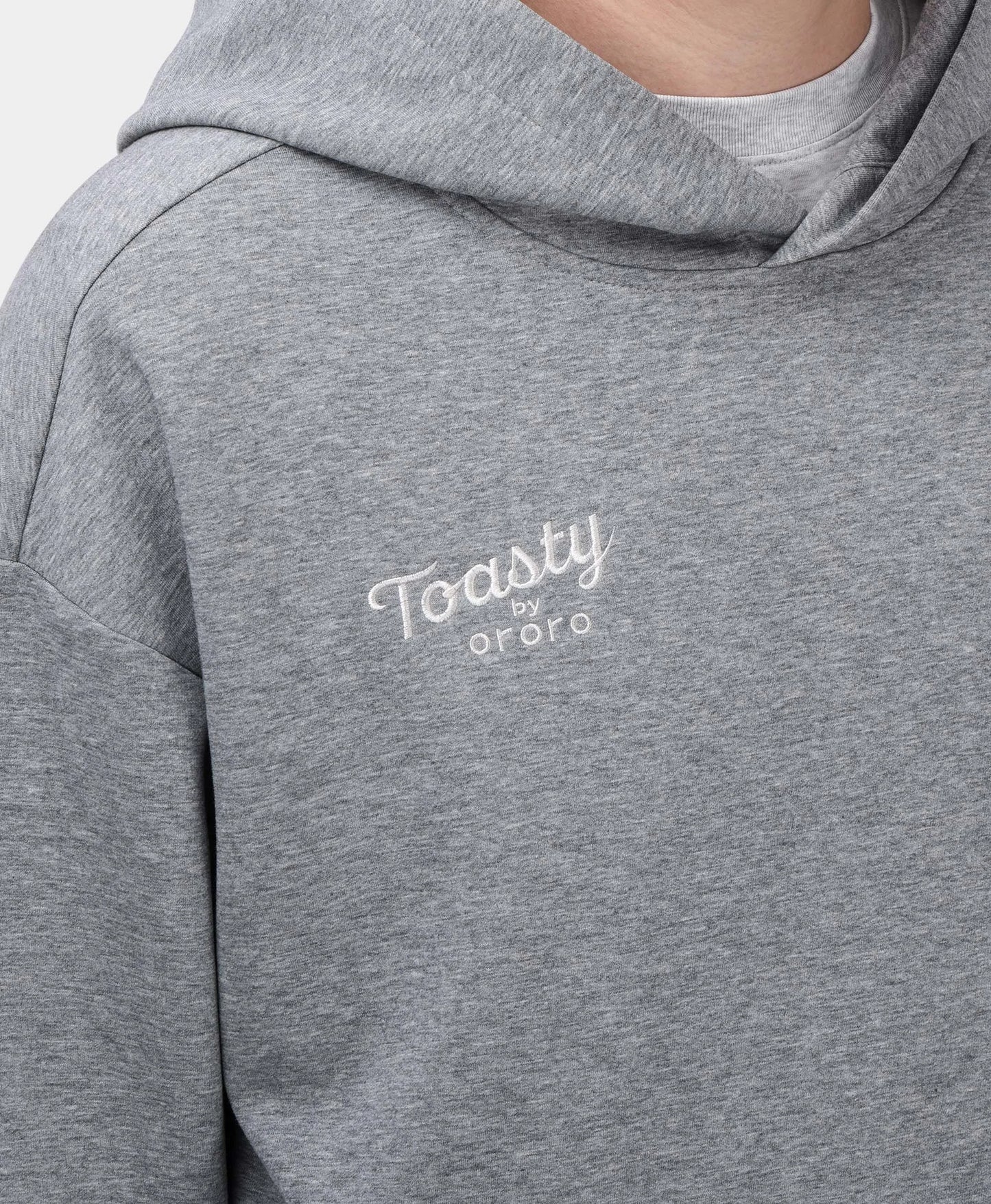 A flecking gray Toasty Unisex 5-Zone Heated Pullover Hoodie, featuring a close-up of the collar area and the white embroidered "Toasty by ororo" logo on the left chest.