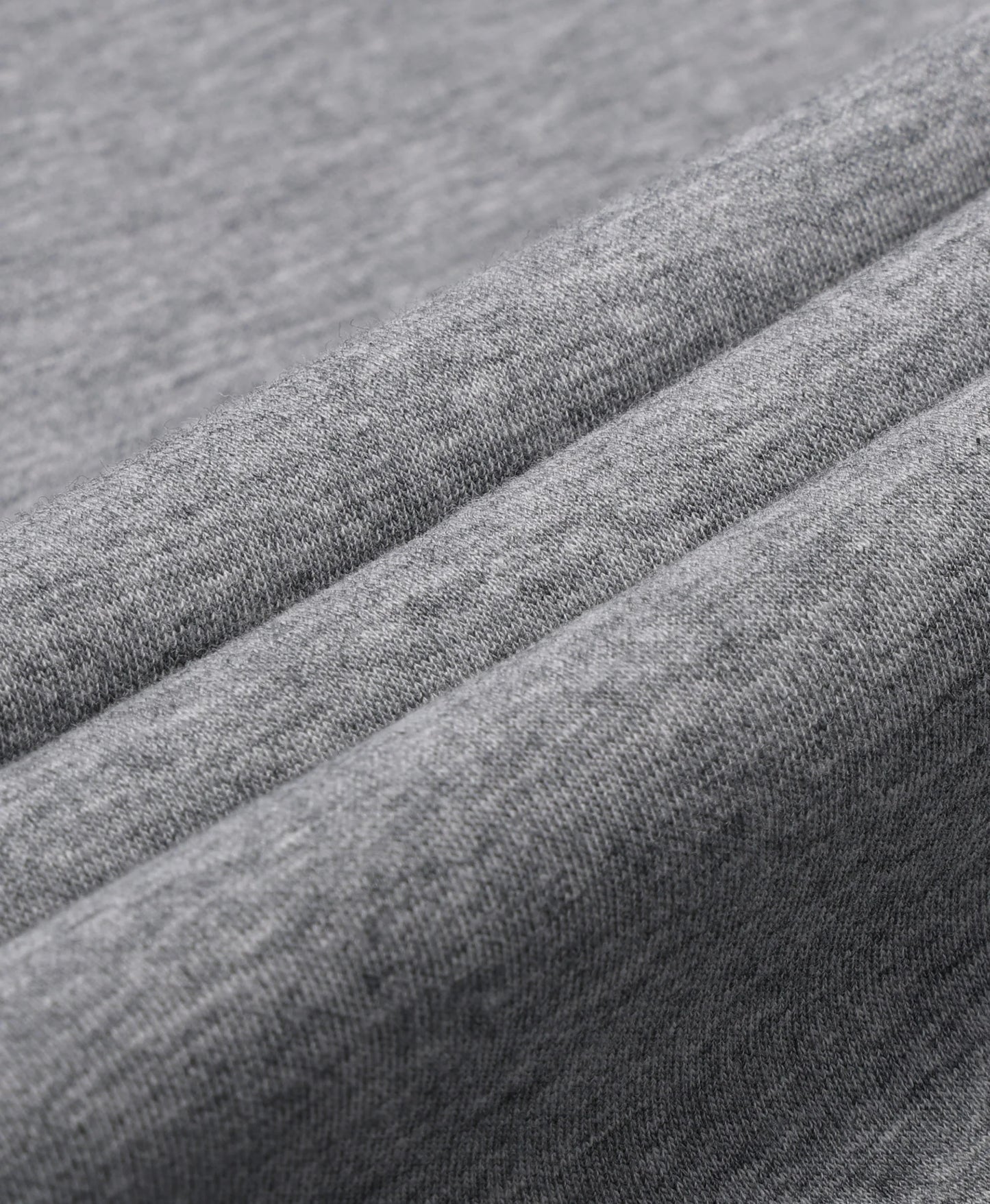 A flecking gray Toasty Unisex 5-Zone Heated Pullover Hoodie, displayed in a macro close-up of draped gray fabric with soft diagonal folds showing a fine woven texture.