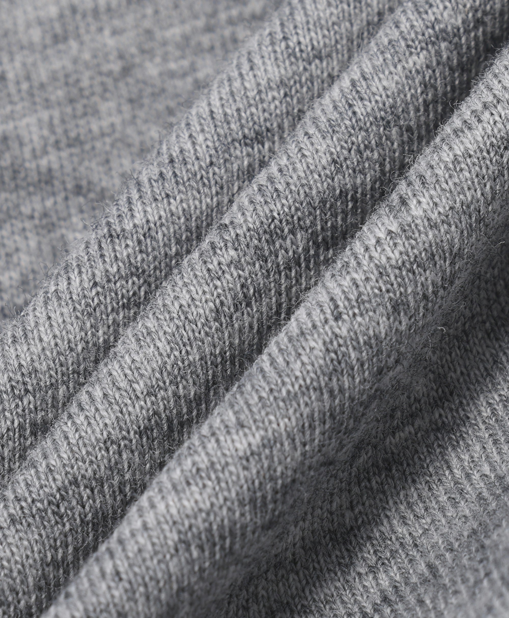Close-up of a heather gray knit fabric with soft diagonal folds showing the texture and weave.