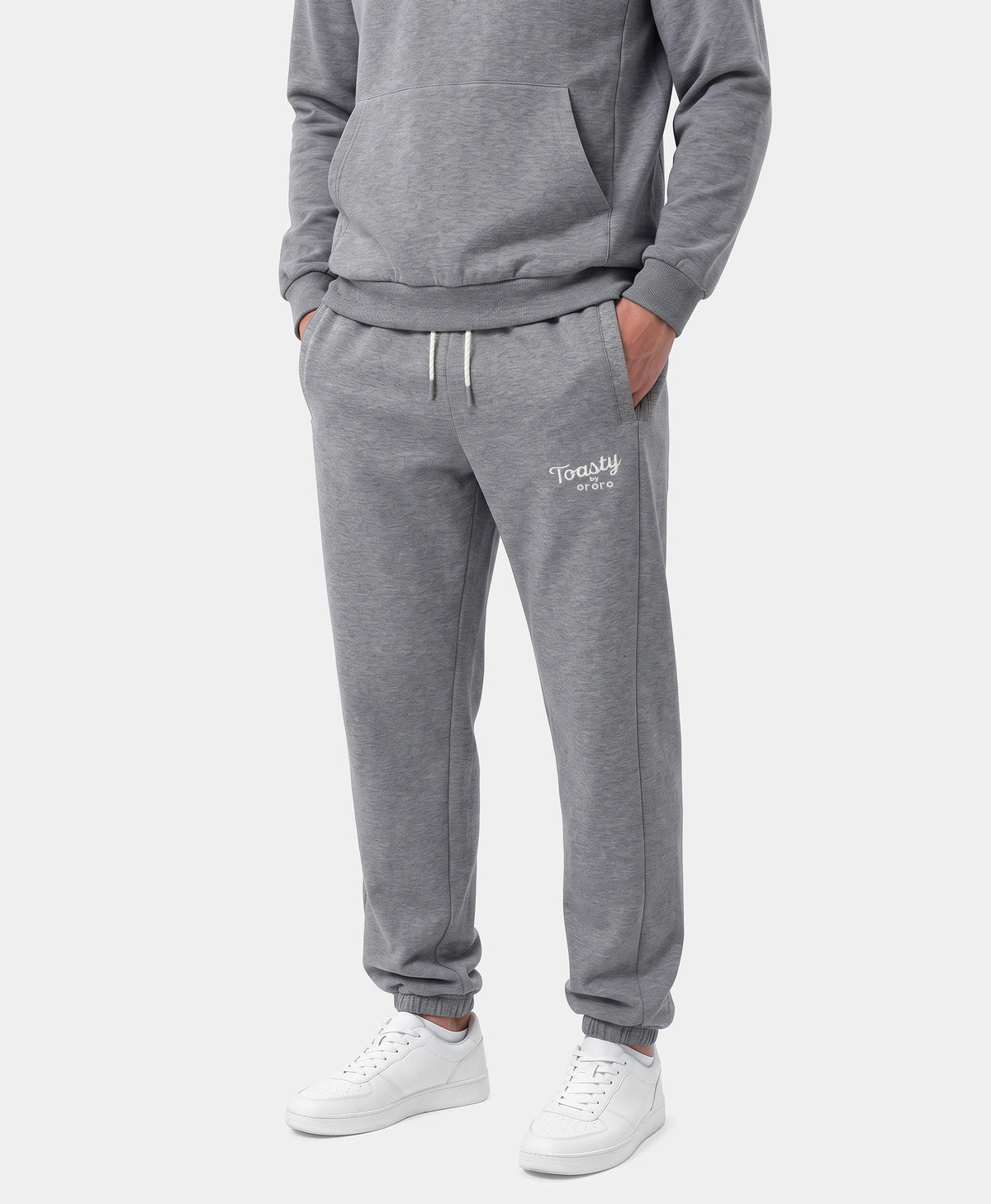 A person wearing Flecking Gray Toasty Heated Sweatpants with white sneakers and a gray sweatshirt