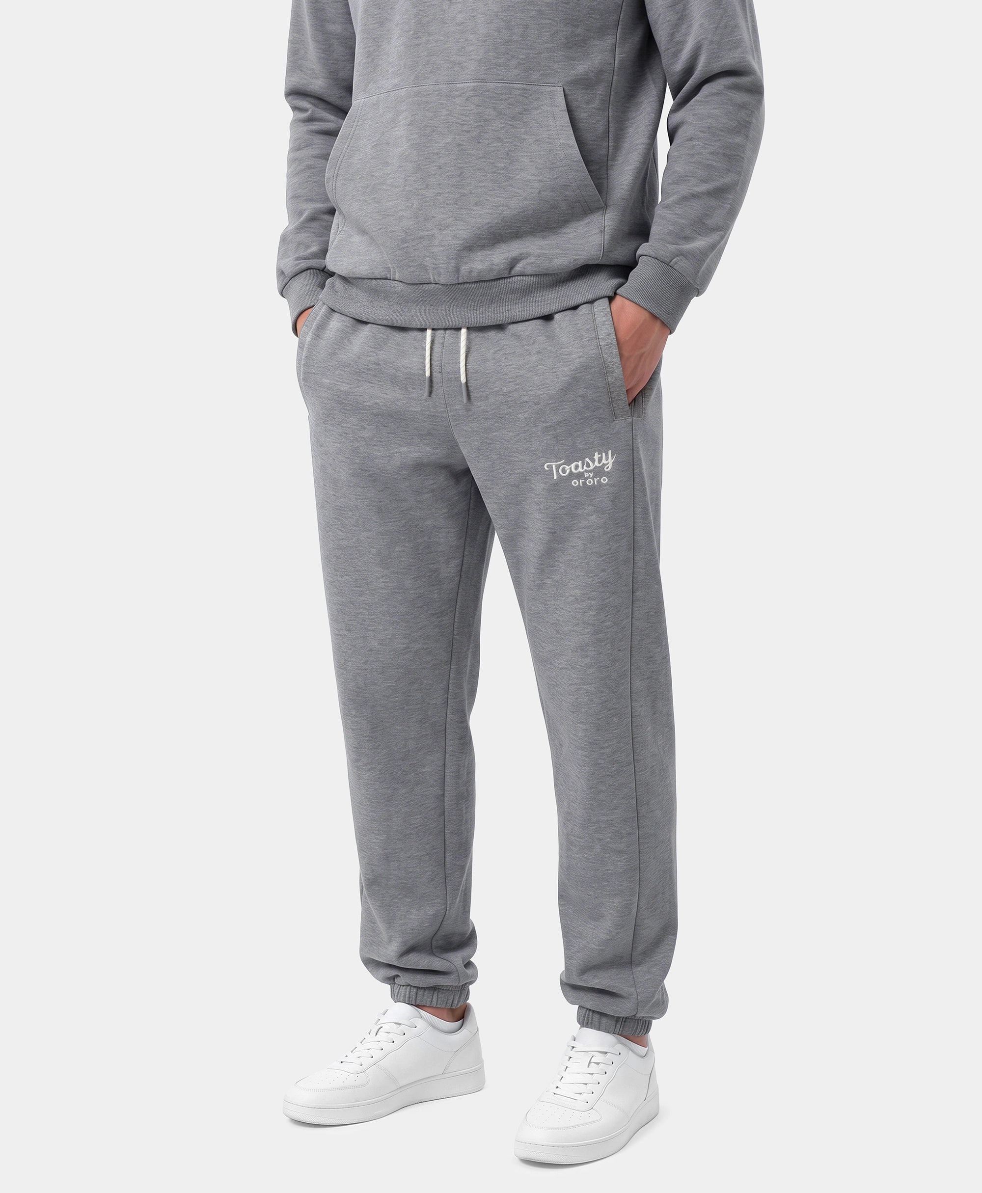 A person wearing Flecking Gray Toasty Heated Sweatpants with white sneakers and a gray sweatshirt