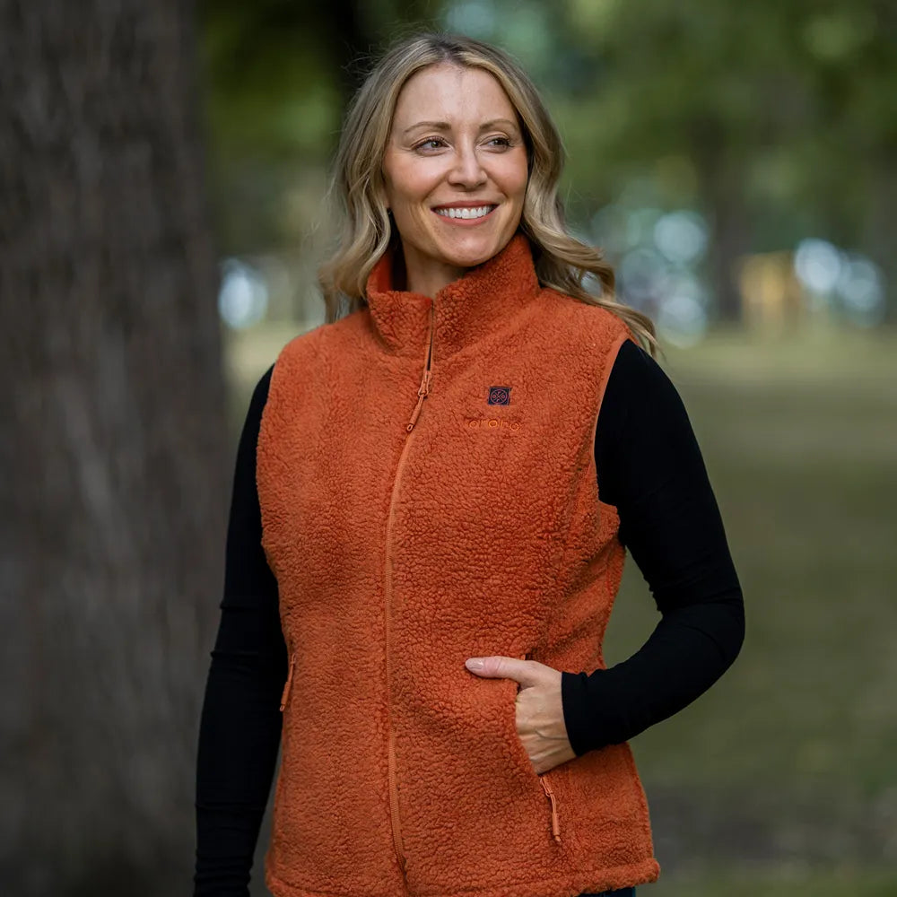 A woman wearing an oeoeo orange sherpa fleece zip-up vest over a black long-sleeve shirt